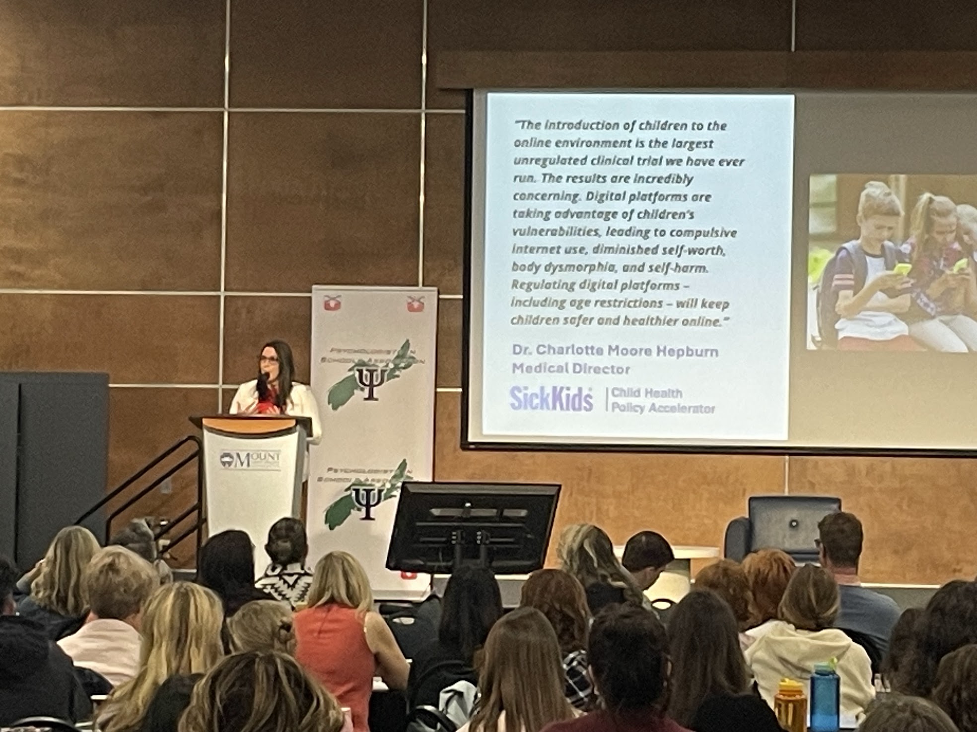 Jenna Poste presenting at Mount Saint Vincent University to a large auditorium audience